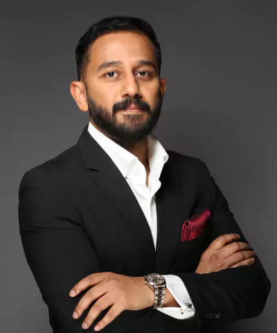 Business professional in formal suit with confident pose against grey background