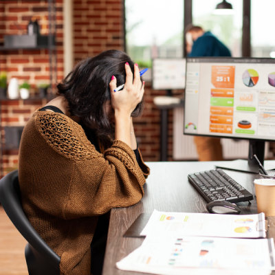 Stressed woman holding her head while sitting at office desk with computer
