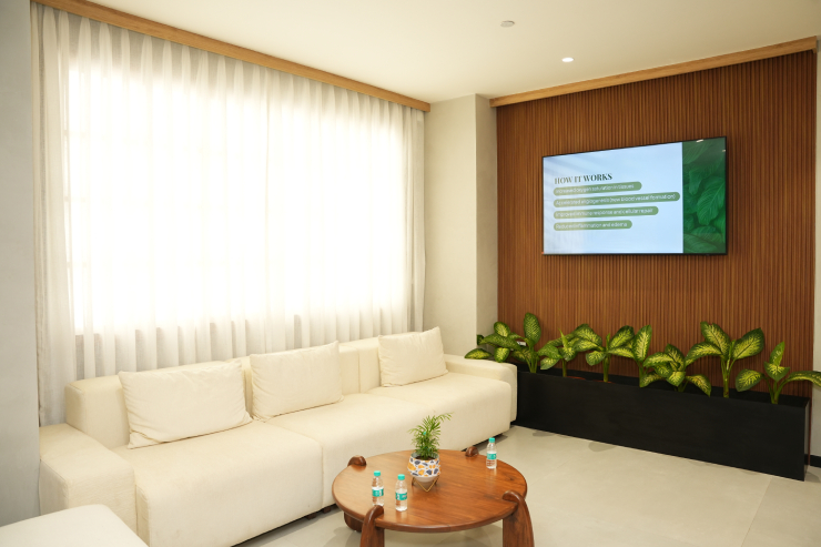 Modern wellness centre waiting lounge with sofa, plants, and display screen