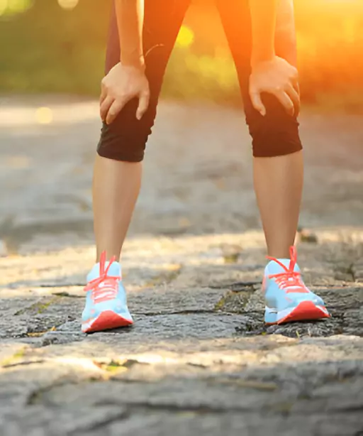 Athlete resting after workout with hands on knees wearing running shoes